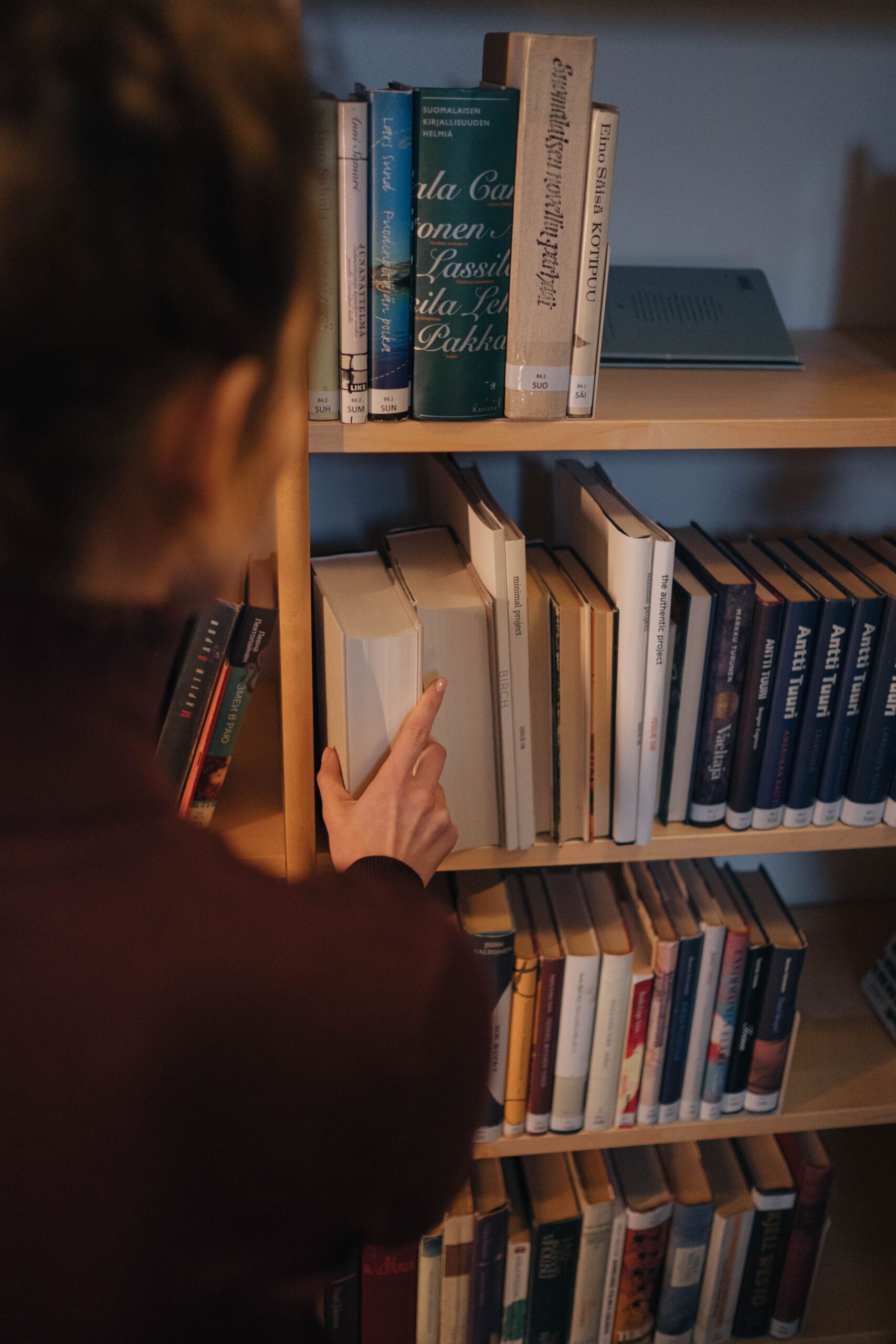 Author exploring a library bookshelf